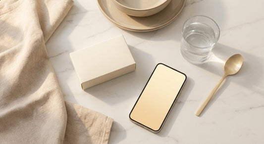 A discreet at-home medical test kit arranged on a white marble surface alongside a glass of water and a smartphone, bathed in soft natural light.
