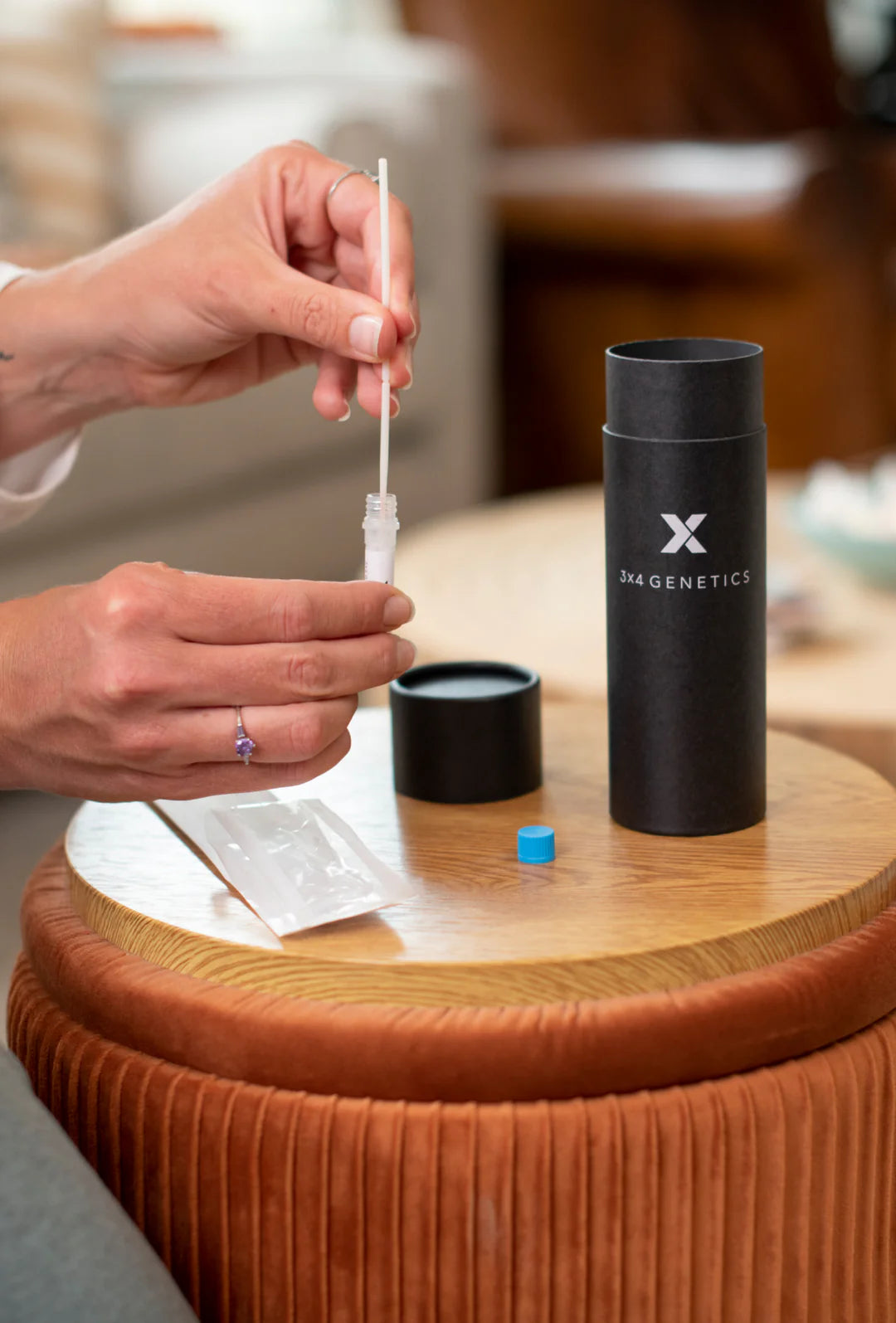 Black cylindrical bottle with X logo as dropper is held over table